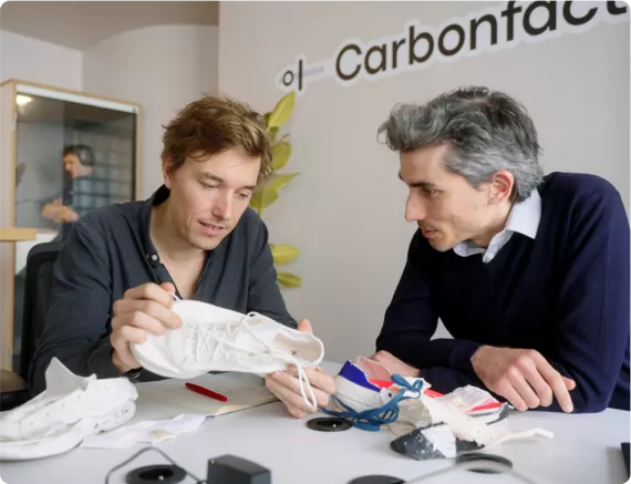 112624_9 Lösungen für den Klimaschutz_Carbonfact Zwei Personen schauen sich einen Sportschuh an